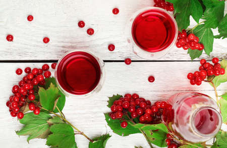 Still life, food and drink, health and homeopathy concept. Viburnum (guelder rose) drink in glass on a wooden table. Selective focus, top viewの写真素材