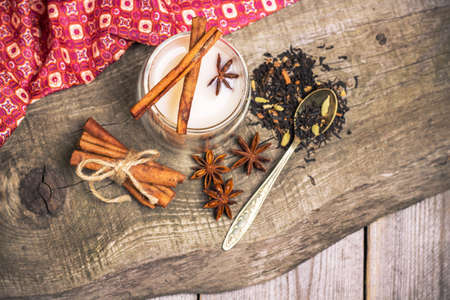 Still life, food and drink concept. Organic masala tea in a glass with spices (anise, cinnamon) on a rustic wooden table. Selective focus, top view, copy spaceの写真素材