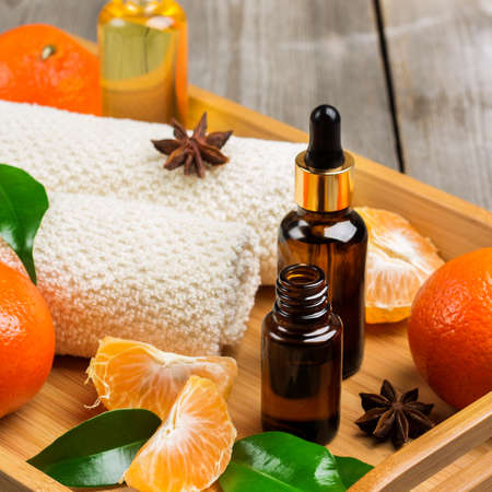 Spa assortment with organic tangerine essential oil in a tray on a rustic wooden table. Selective focusの写真素材