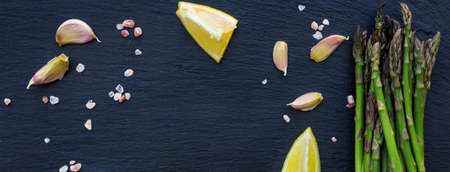 Healthy concept. Bunch of organic fresh asparagus with ingredients for cooking on a grunge stone table. Selective focus, copy space background, flat layの写真素材