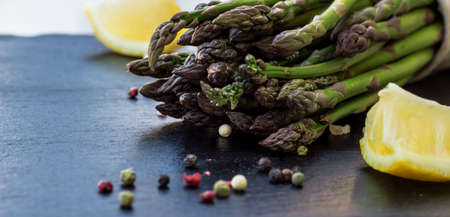 Healthy concept. Bunch of organic fresh asparagus with ingredients for cooking on a grunge stone table. Selective focusの写真素材