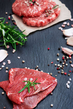 Fresh raw meat and burger cutlets from the farmers market on a black grunge table. Selective focusの写真素材