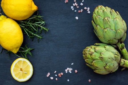 Organic fresh artichokes with lemon with copy space, grunge background. Selective focus, top viewの写真素材