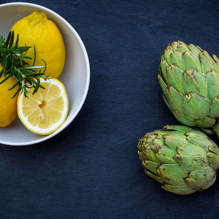 Organic fresh artichokes with lemon with copy space, grunge background. Selective focus, top viewの写真素材
