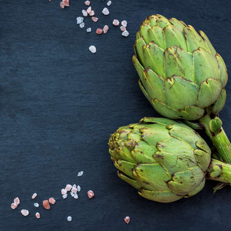 Organic fresh artichokes with salt, copy space, grunge background. Selective focus, top viewの写真素材