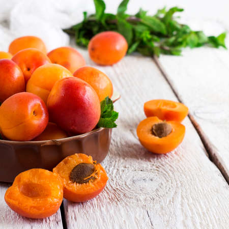 Food and drink, healthy nutrition concept. Ceramic bowl with organic ripe apricots on a rustic wooden white table. Selective focus, summer compositionの写真素材