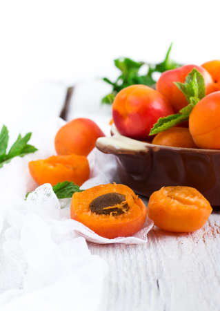 Food and drink, healthy nutrition concept. Ceramic bowl with organic ripe apricots on a rustic wooden white table. Selective focus, summer compositionの写真素材