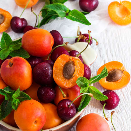 Food and drink, healthy nutrition concept. Ceramic bowl with organic ripe apricots and cherries on a...