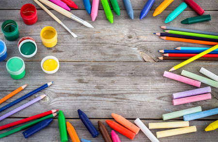 Education and business concept. School supplies with crayons, paint, chalk on a copy space wooden background. Selective focusの写真素材