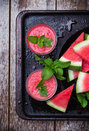 Still life, food and drink, diet concept. Organic fresh watermelon slices with mint and drink smoothie on a grunge black table. Selective focus, top viewの写真素材
