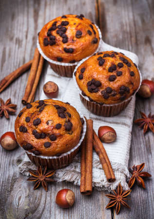 Food and drink, seasonal concept. Homemade chocolate chip muffins with nuts and anise stars, cinnamon for breakfast on a rustic wooden table. Selective focusの写真素材