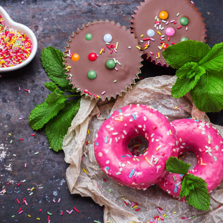 Junk, unhealthy food concept. Colorful pink donuts with green mint on a grunge rusty table. Selective focus, top view, flat layの写真素材