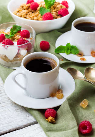 Breakfast, food, still life concept. Coffee muesli granola berries homemade yogurt on a white wooden table. Selective focusの写真素材