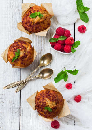 Still life, food and drink, breakfast concept. Fresh homemade muffins with raspberry on a rustic white wooden table. Selective focus, top view flat layの写真素材