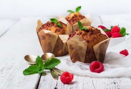 Still life, food and drink, breakfast concept. Fresh homemade muffins with raspberry on a rustic white wooden table. Selective focusの写真素材
