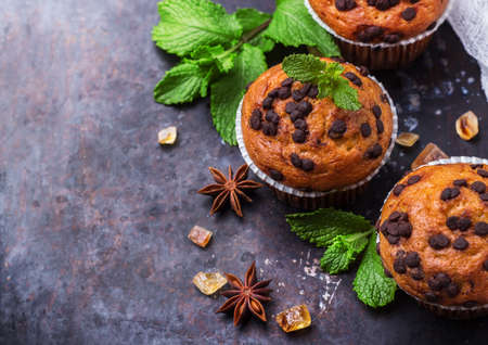 Food and drink, seasonal concept. Homemade chocolate chip muffins with green mint for breakfast on a grunge rusty pan. Selective focus, copy space backgroundの写真素材