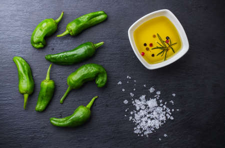 Food and drink, still life, moody concept. Raw green peppers pimientos de padron mexican jalapeno spanish tapas olive oil sea salt on a wooden table. Selective focus, top view flat lay overheadの写真素材