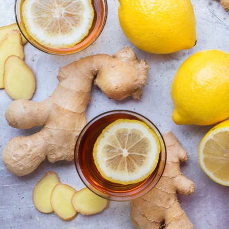 Ginger tea in a glass with ingredients. Hot drink with lemon for cold flu winter autumn on a rustic metal table. Selective focus, top view flat layの写真素材