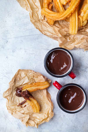 Fast junk unhealthy fat food concept. Spanish churros with hot chocolate in a mug on a rustic table. Treat for traditional typical breakfast, top view overhead flat layの写真素材