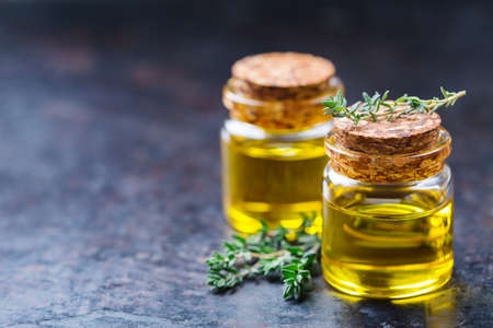 Health and beauty, still life concept. Organic essential thyme oil in a small glass jar with green leaves. Copy space backgroundの写真素材