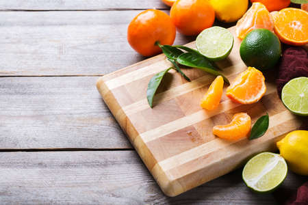 Healthy food, diet, nutrition, nature concept. Assortment of citrus fruits, vitamin background. Orange, grapefruit, tangerine, lime, lemon with leaves on a rustic wooden cutting board, copy spaceの写真素材