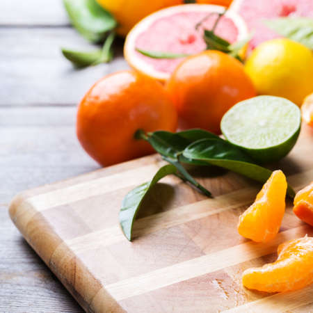Healthy food, diet, nutrition, nature concept. Assortment of citrus fruits, vitamin background. Orange, grapefruit, tangerine, lime, lemon with leaves on a rustic wooden cutting board, copy spaceの写真素材