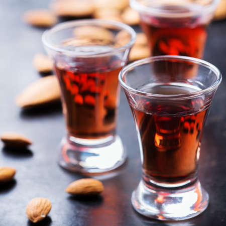 Food and drink, party, alcohol concept. Traditional italian sweet almond liquor amaretto on a grunge black table, digestif beverageの写真素材
