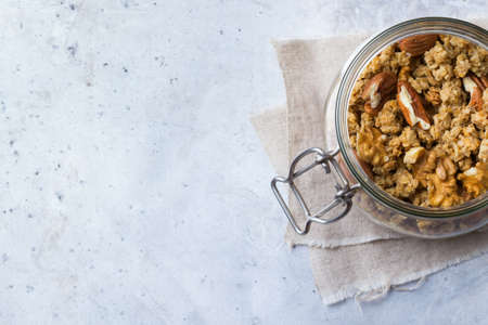 Breakfast, healthy food concept. Homemade muesli granola with nuts in a jar on a table. Selective focus, copy space background, top view flat lay overheadの写真素材
