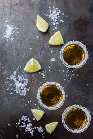 Alcohol, junk food, party, holidays concept. Golden mexican tequila shot on a grunge black table with salt and lime. Copy space background, top view flat lay overheadの写真素材