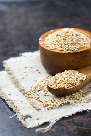 Healthy food and drink concept. Sesame seeds in a bowl and spoon on a rustic table. Copy space...