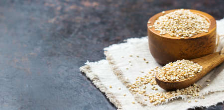 Healthy food and drink concept. Sesame seeds in a bowl and spoon on a rustic table. Copy space...