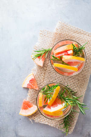Healthcare, fitness, healthy nutrition concept. Fresh cool grapefruit rosemary infused water, cocktail, detox drink, lemonade for spring summer days. Top view overhead flat lay, copy space backgroundの写真素材