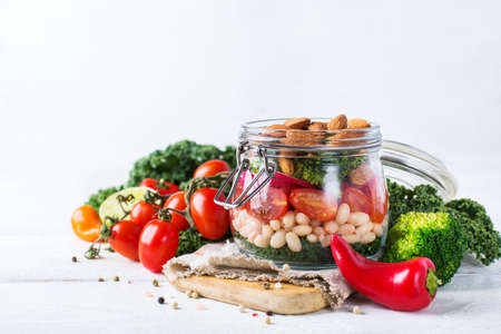 Health care, diet and nutrition concept. Vegan salad in a mason jar with vegetables beans and almond...