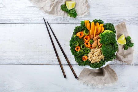 Health care, diet and nutrition concept. Buddha bowl with chopsticks on a white rustic wooden table, vegetarian vegan raw balanced detox meal food. Top view flat lay overheadの写真素材