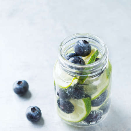 Health care, fitness, healthy nutrition diet concept. Fresh cool lemon lime berries blueberry infused water, cocktail, detox drink, lemonade for spring summer daysの写真素材