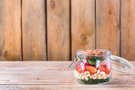 Health care, diet and nutrition concept. Vegan salad in a mason jar with vegetables beans on a rustic wooden table, vegetarian raw balanced detox meal food. Copy space backgroundの写真素材