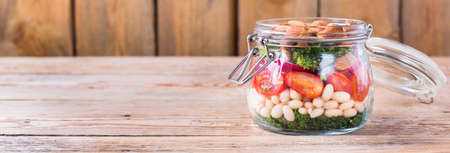 Health care, diet and nutrition concept. Vegan salad in a mason jar with vegetables beans on a rustic wooden table, vegetarian raw balanced detox meal food. Copy space backgroundの写真素材