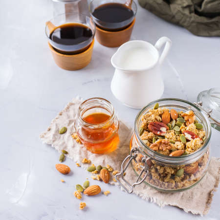 Healthy diet nutrition food concept. Homemade muesli granola with honey nuts milk and black coffee for early morning breakfast. Modern minimalism style backgroundの写真素材
