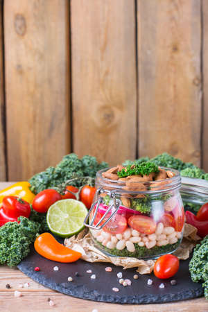 Health care, diet and nutrition concept. Vegan salad in a mason jar with vegetables beans on a rustic wooden table, vegetarian raw balanced detox meal food. Copy space backgroundの写真素材