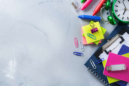 Back to school, children education concept. Assortment of supplies, crayons, pens and alarm clock on...