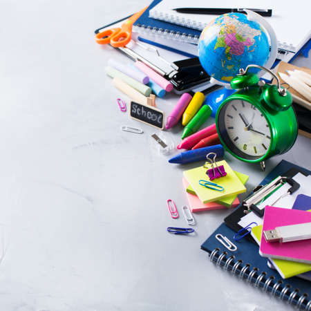 Back to school, children education concept. Assortment of supplies, crayons, pens and alarm clock on...