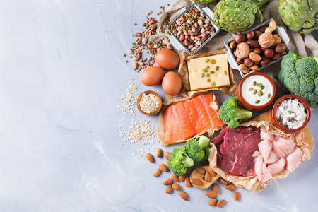 Assortment of healthy protein source and body building food. Meat beef salmon chicken breast eggs dairy products cheese yogurt beans artichokes broccoli nuts oat meal. Copy space background, top viewの写真素材