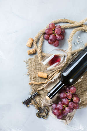 Food and drink, still life, holidays seasonal harvesting fall concept. Bottle, corkscrew, corks, glass of red wine and grapes on a trendy concrete table. Copy space background, top view flat layの写真素材