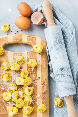 Assortment of italian food and ingredients, handmade tortellini with ricotta on a table. Top view flat layの写真素材