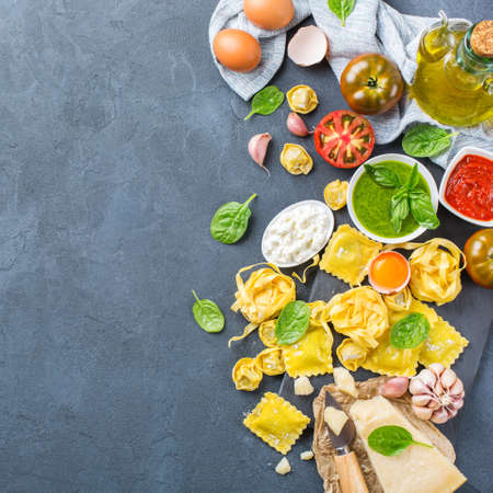 Assortment of italian food and ingredients, ravioli with ricotta and spinach pasta tortellini pesto tomato sauce olive oil parmesan cheese. Copy space background, top view flat layの写真素材