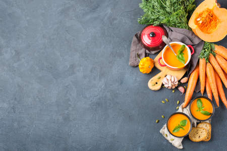 Food and drink, still life, diet and nutrition concept. Seasonal fall autumn roasted orange pumpkin carrot soup with ingredients on a rustic wooden table. Copy space top view cozy kitchen backgroundの写真素材