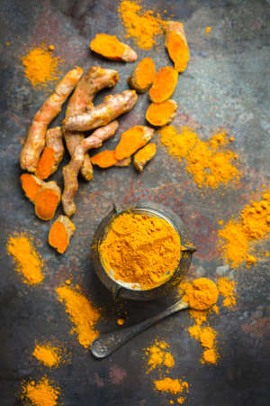 Food and drink, diet nutrition, health care concept. Organic orange turmeric root and powder, curcuma longa on a grunge cooking table. Indian oriental low cholesterol spices. Top view flat layの写真素材