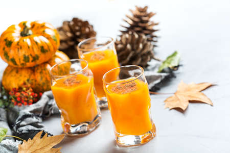 Food and drink, seasonal autumn thanksgiving holidays concept. Orange alcohol shot drink cocktail beverage on a table with fall decoration with pumpkins and leavesの写真素材