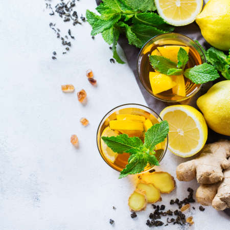 Japanese chinese tea with lemon ginger honey mint on a white table. Warm drink beverage infusion in glass for cold flu winter fall days. Coy space background, top view flat layの写真素材