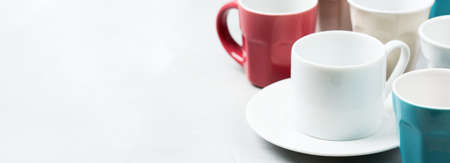 Breakfast relaxation time restaurant concept. Different white empty coffee and tea mugs and cups on a cozy kitchen table. Copy space backgroundの写真素材